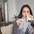 Ill korean woman looking at thermometer with concerned face, catching cold, having fever, having covid, staying at home on sick leave.